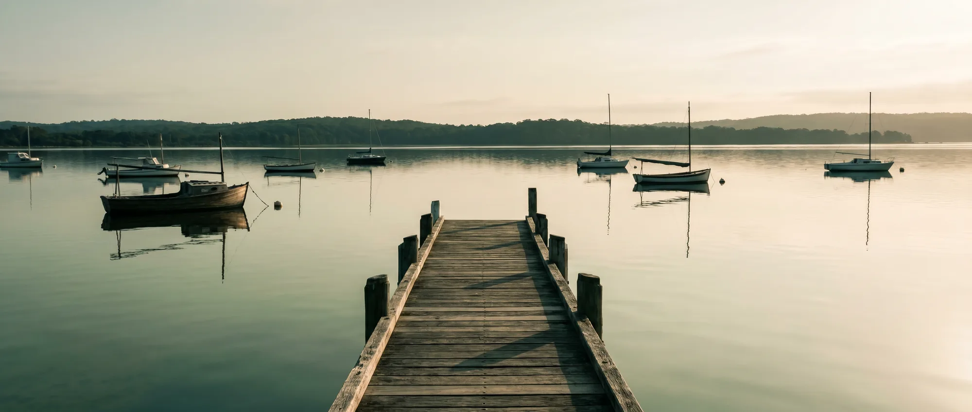 Lake Macquarie flat and still at dawn from the Toronto foreshore, a timber jetty reaching into the water